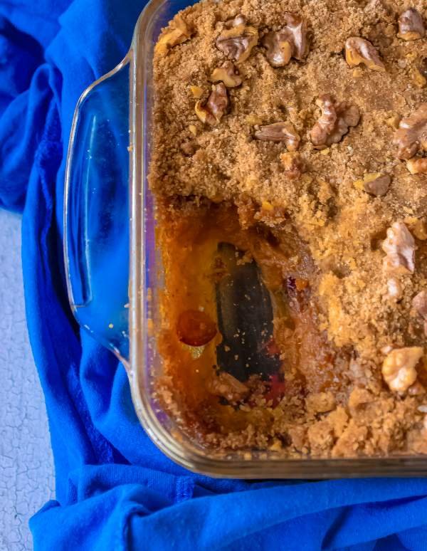 Casserole dish with with one scoop taken out of it and wrapped with a blue cloth