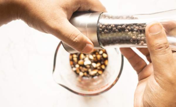 adding cracked pepper to sauce