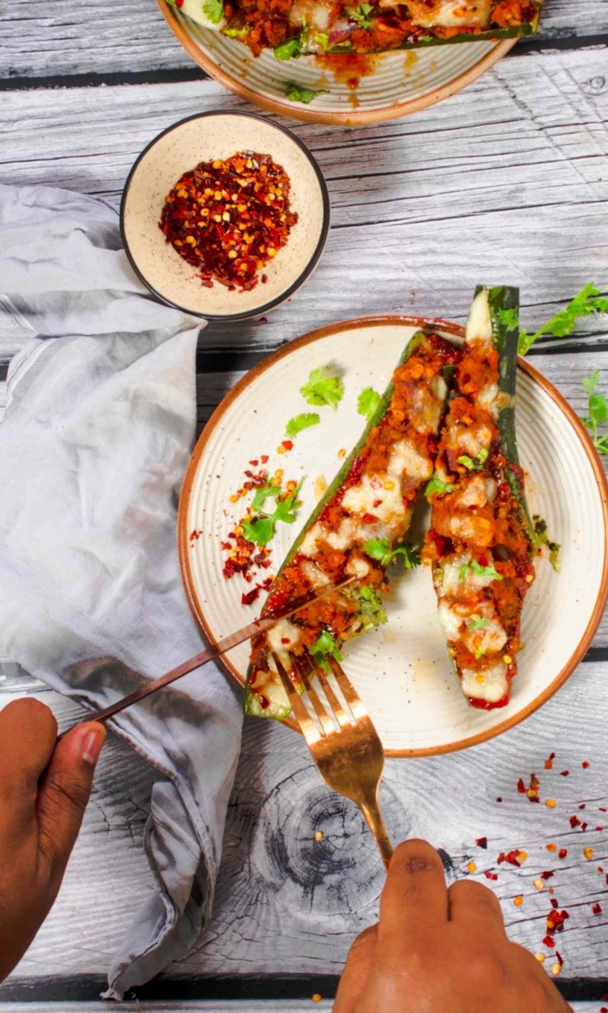 slicing zucchini boats with a fork and a knife